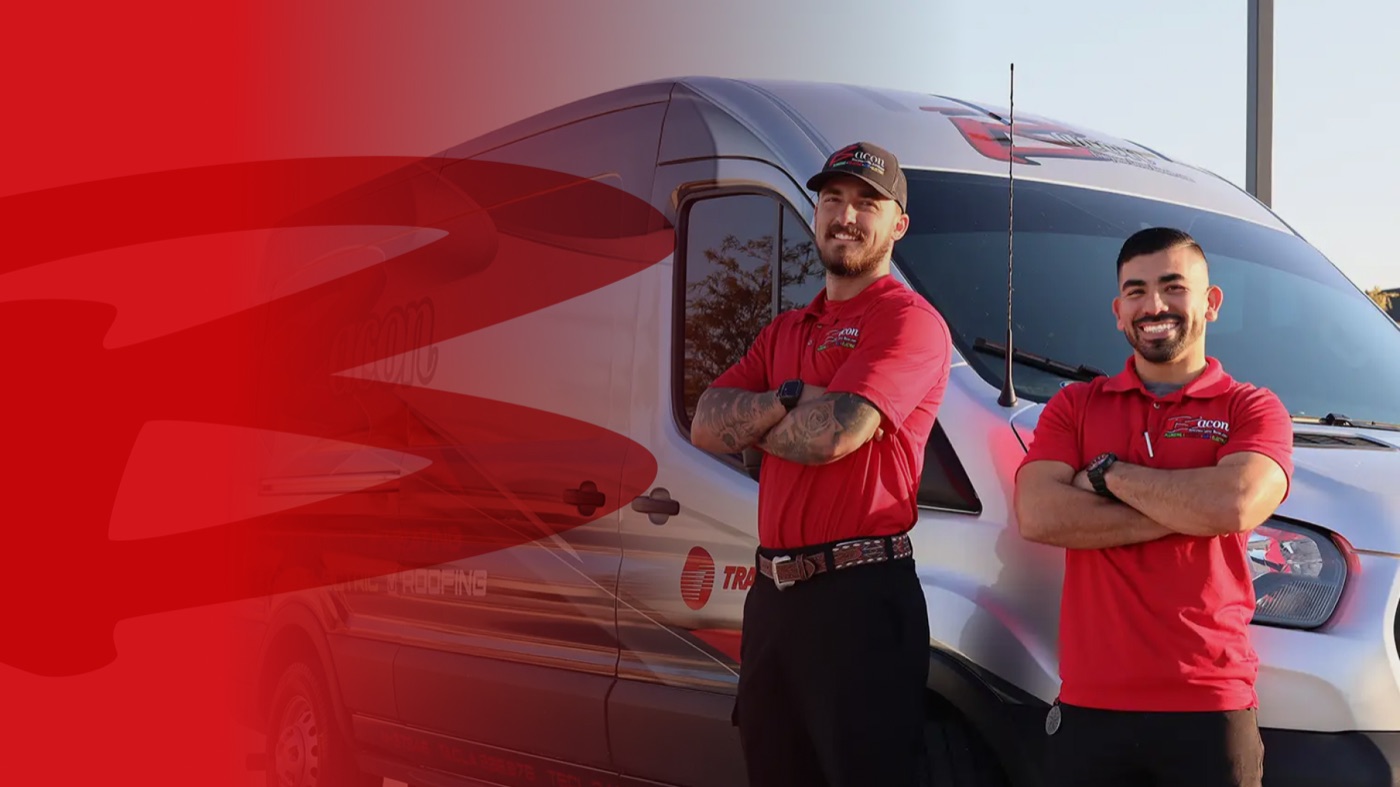 Two Bacon technicians in red company shirts standing beside a branded service van