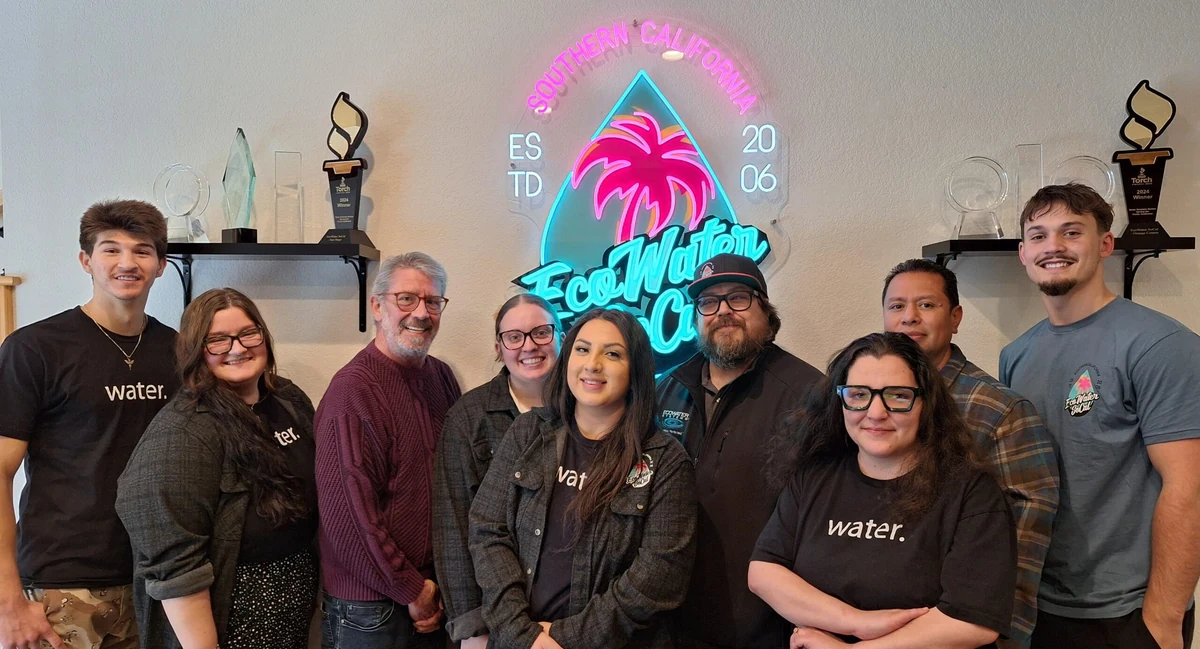 EcoWater SoCal customer-service team standing in front of the company’s neon palm logo